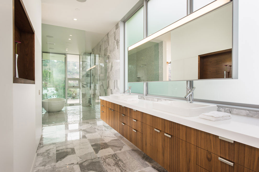 The master vanity and mirror floating in front of a frosted window.