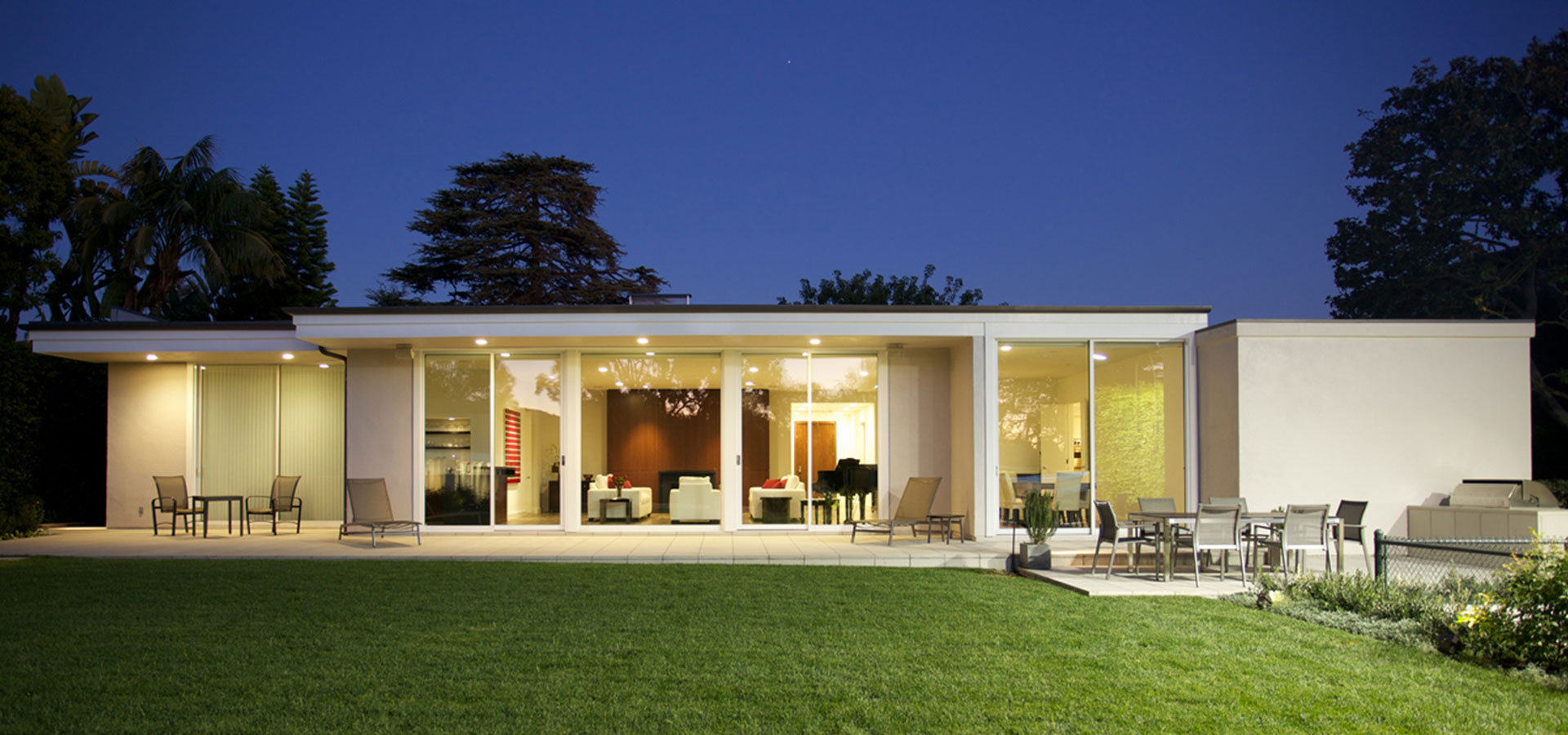 A view of the Brentwood Residence, a restored mid century home, from the backyard at night