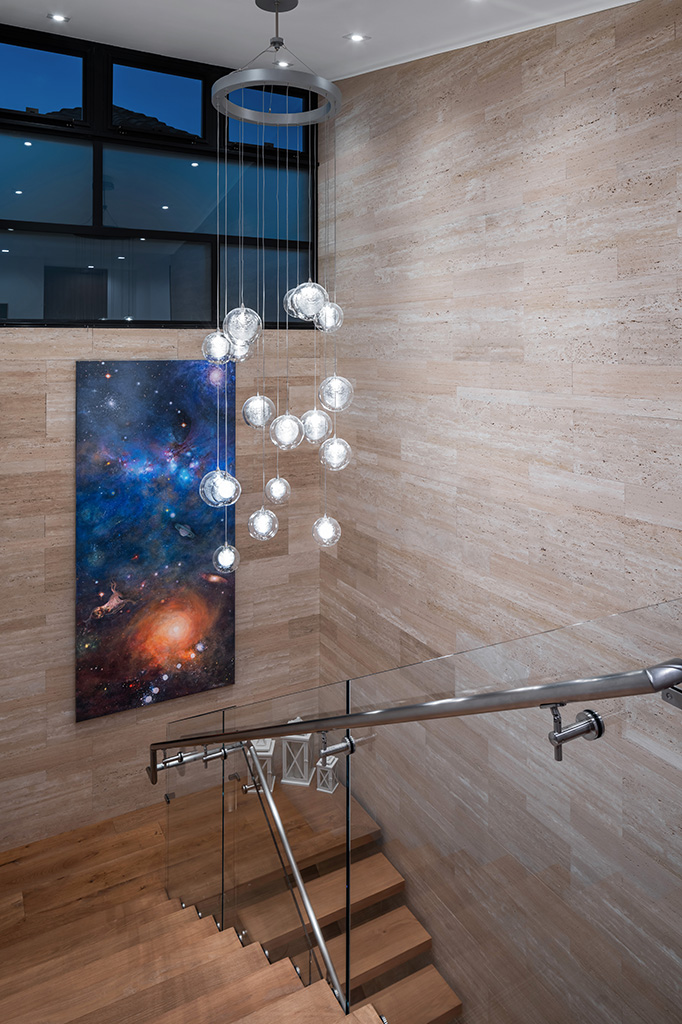 The stair from the second floor landing at night with the custom chandelier designed by Casa Stilo. Photo: ©Paul Vu, Here and Now Agency