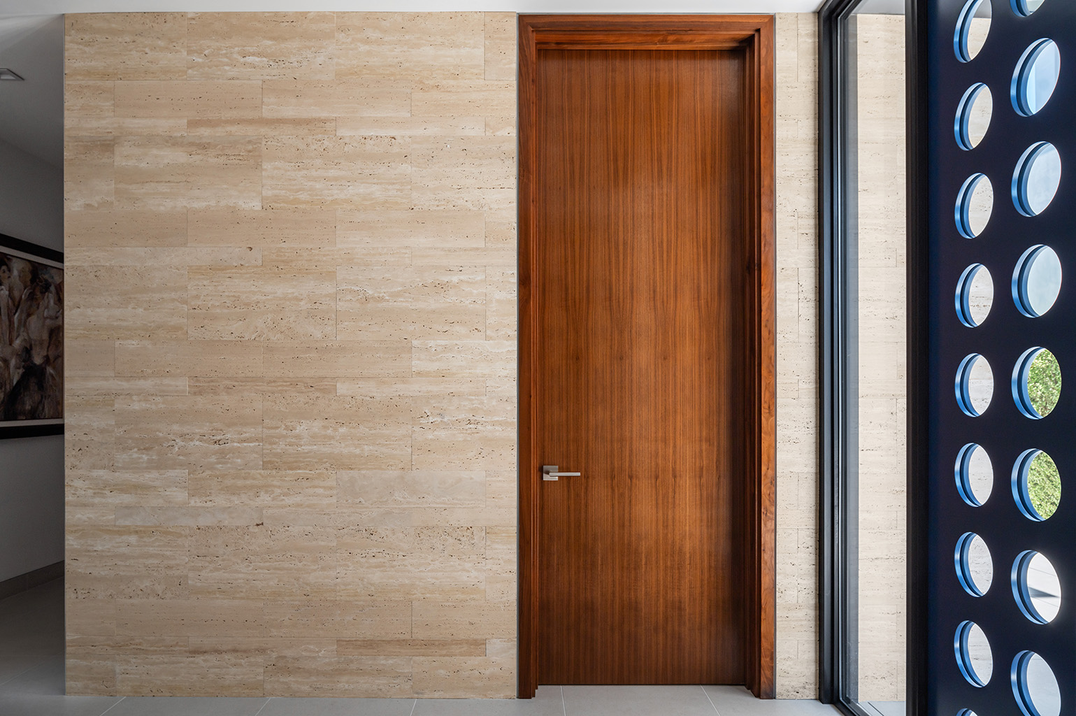 Travertine wraps from the exterior to the interior and eventually around the stair. This detail shows both the front door and a typical interior door. Photo: ©Paul Vu, Here and Now Agency