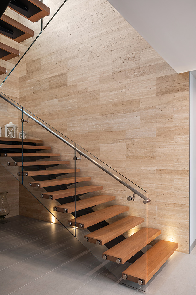 Travertine walls wrap around the custom steel, word and glass open stair. Photo: ©Paul Vu, Here and Now Agency